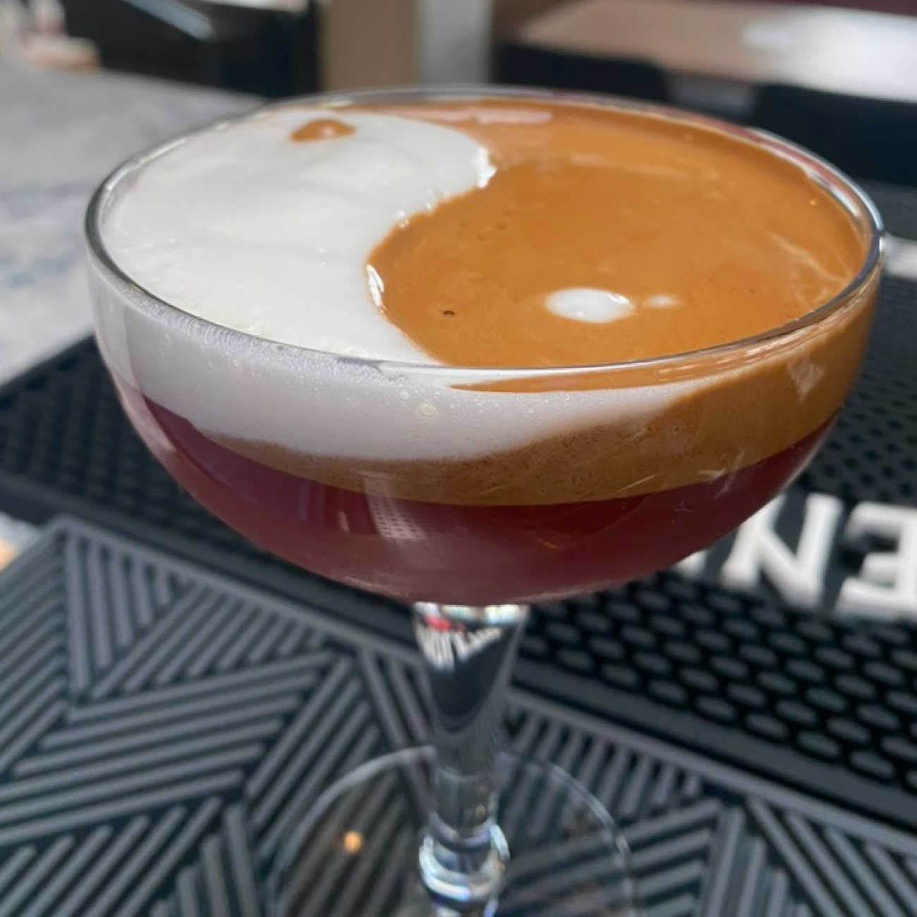 One of Elliot's handcrafted cocktails with a yin yang design on the surface.